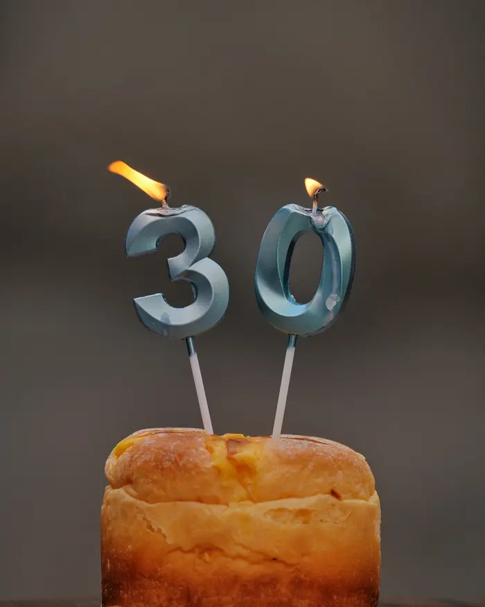 A small birthday cake with number 3 and 0 candles