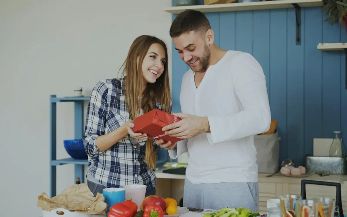 A couple smiling at each other in their kitchen