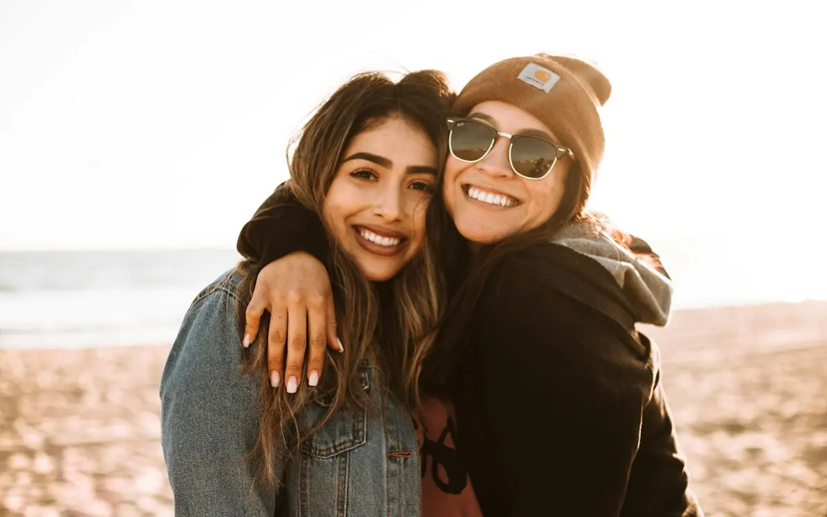 Two best friends hugging and smiling on a beach