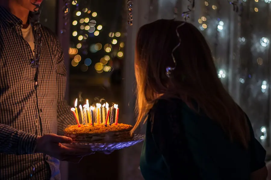 A birthday cake with lit candles on a table at home