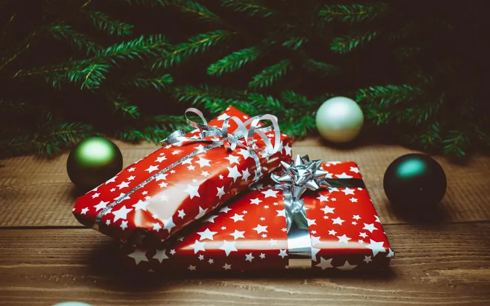 Red wrapped Christmas gifts with ornaments on a wooden table
