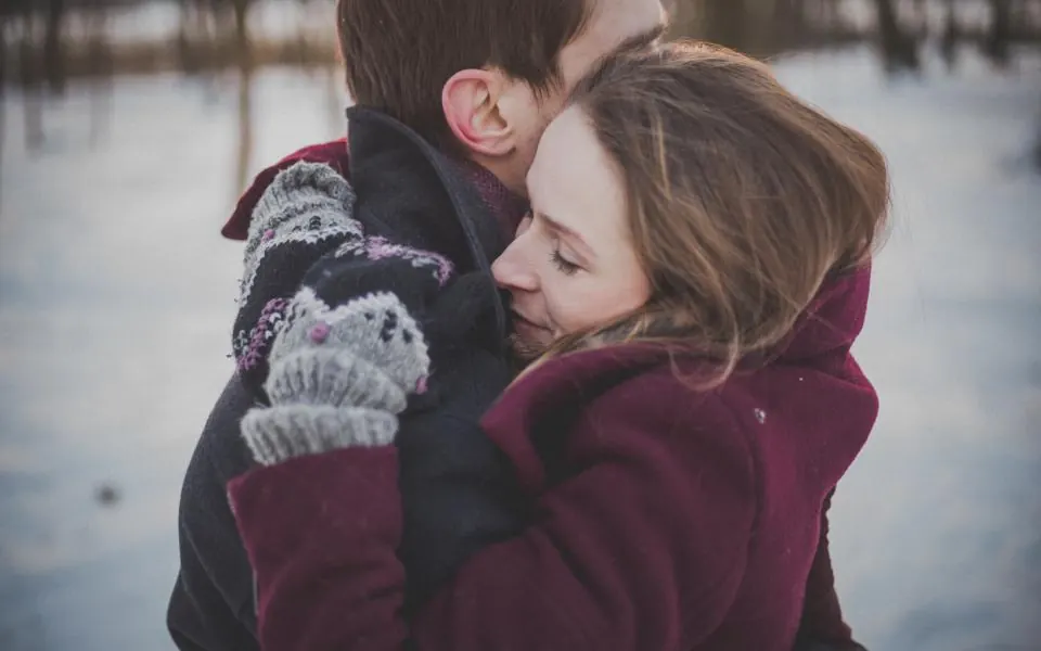 A couple hugging outside on a snowy winter day
