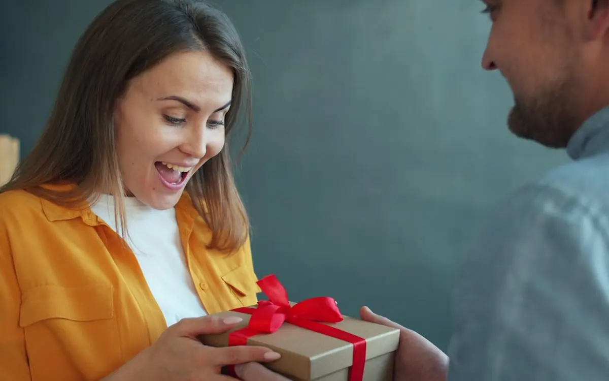 A woman smiling as she opens a birthday gift from her boyfriend