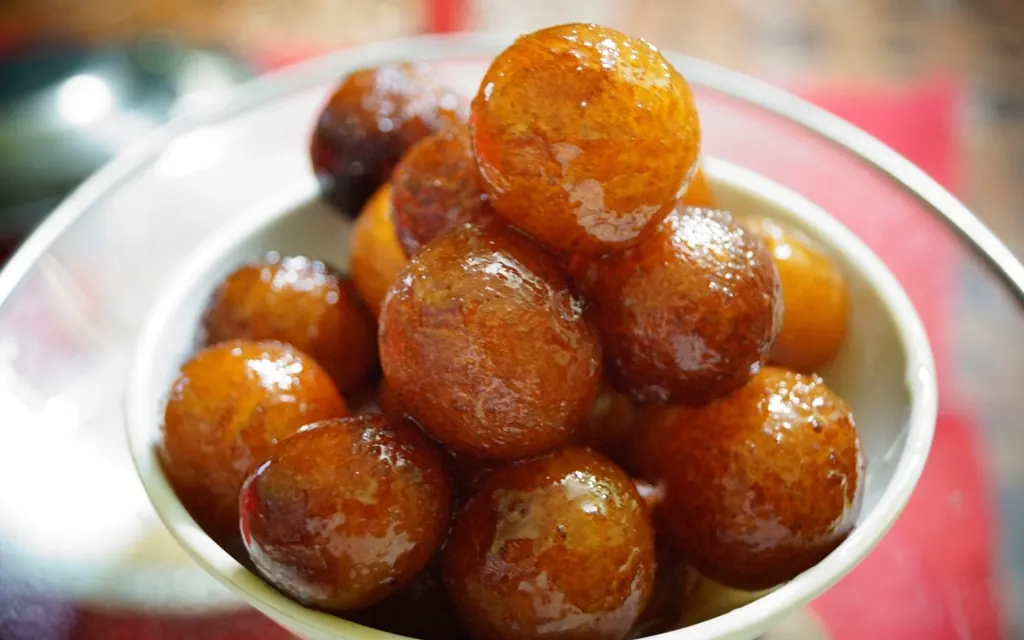 A bowl of glossy gulab jamun in syrup