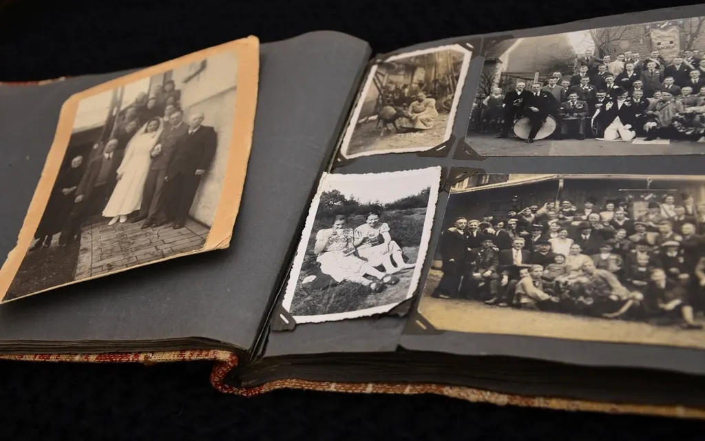 An open vintage photo album with old black and white family photos on dark pages