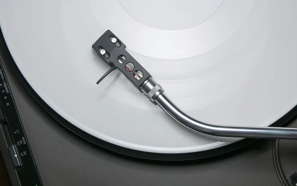 A turntable needle resting on a white vinyl record
