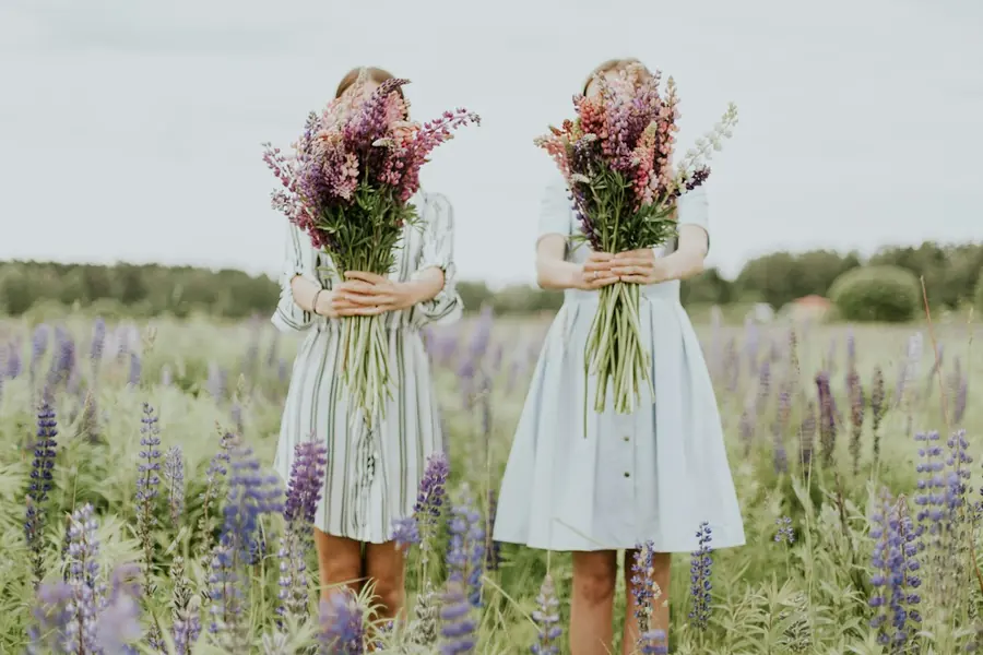 Two sisters holding wildflower bouquets in a field