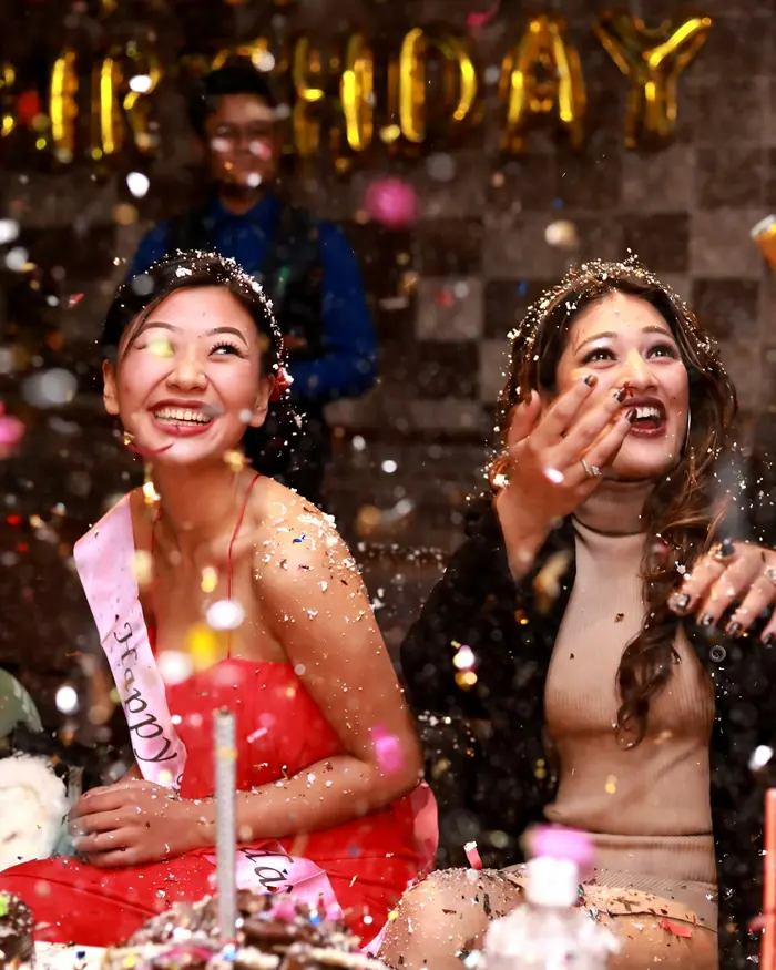 Two friends laughing as they throw glitter at a birthday party