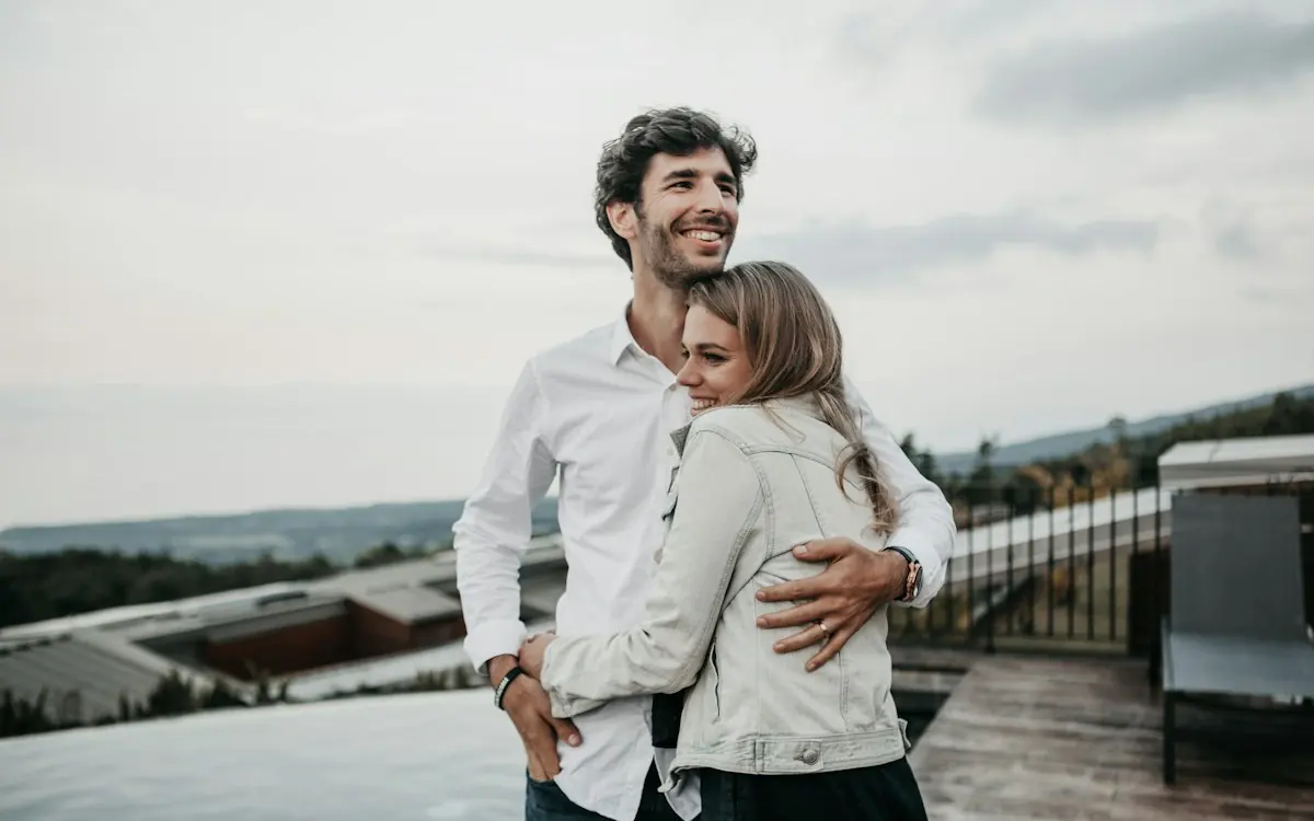 A husband and wife hugging and laughing outdoors